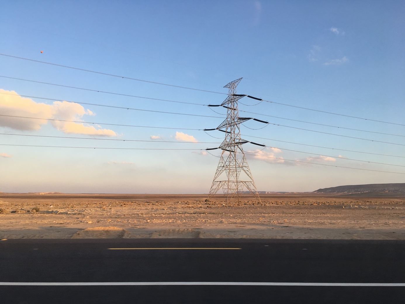 Power pole and lines against blue sky in desert landscape