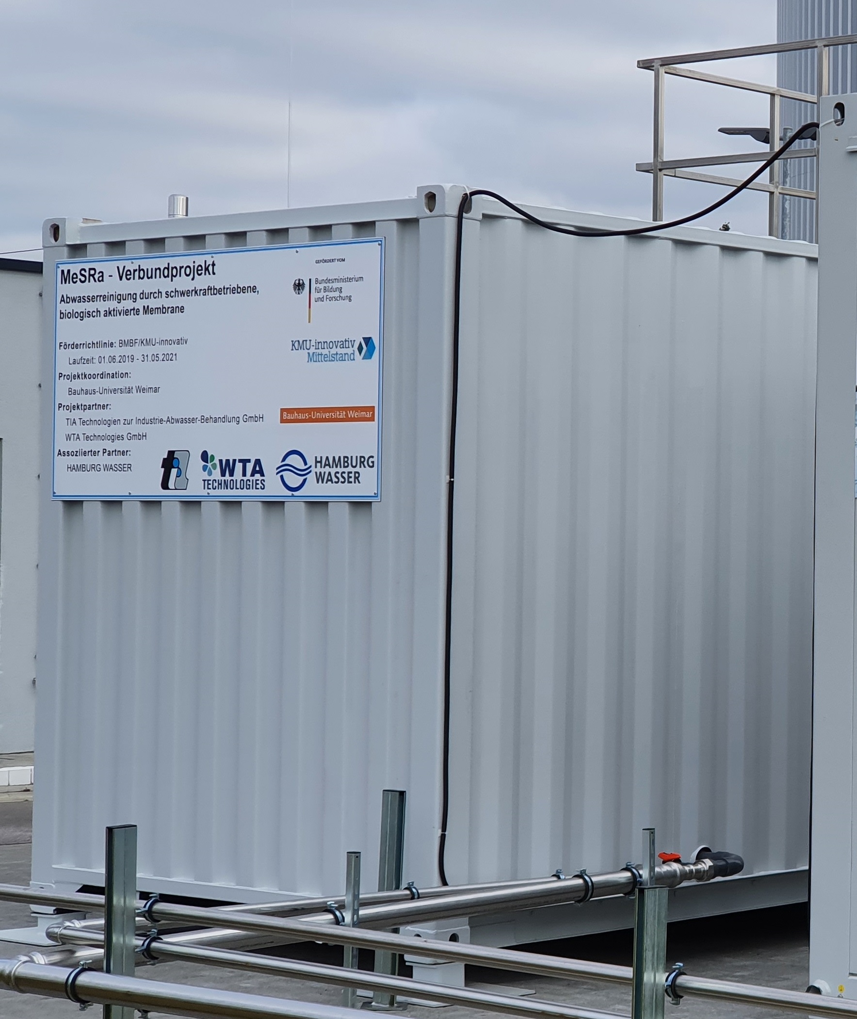 Auf diesem Foto ist ein Anlagen-Container an einer Betriebsstätte zu sehen. Er ist verrohrt und steht auf Stellfüßen.